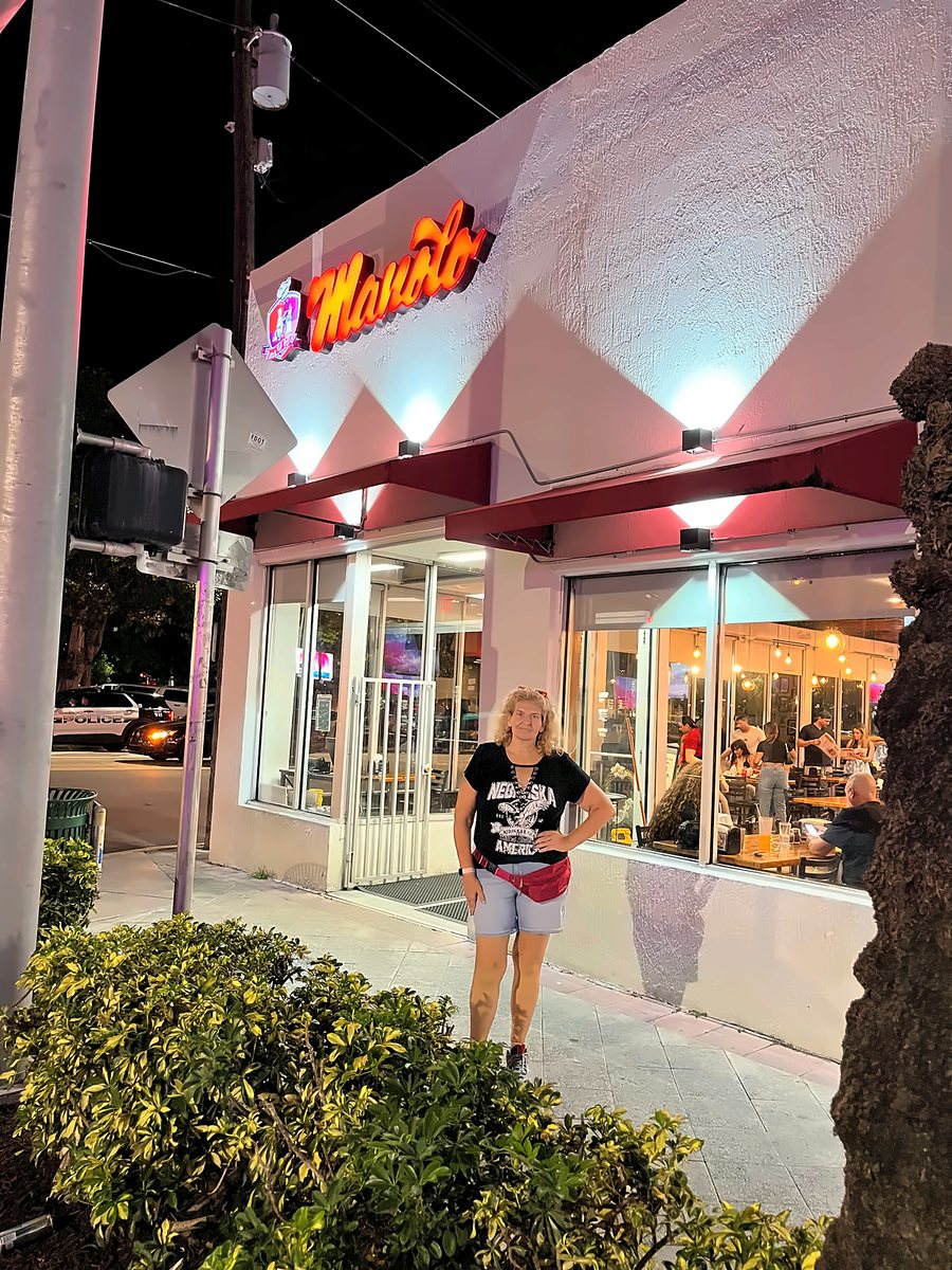 Viajera frente a un restaurante iluminado de noche en Miami